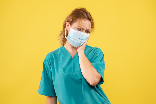 女医生黄色墙壁上穿着医疗服 戴着口罩的女医生的正视图约束医疗肖像