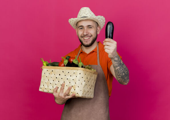 园艺微笑的男园丁戴着园艺帽 手里拿着菜篮子和茄子帽子空间花园
