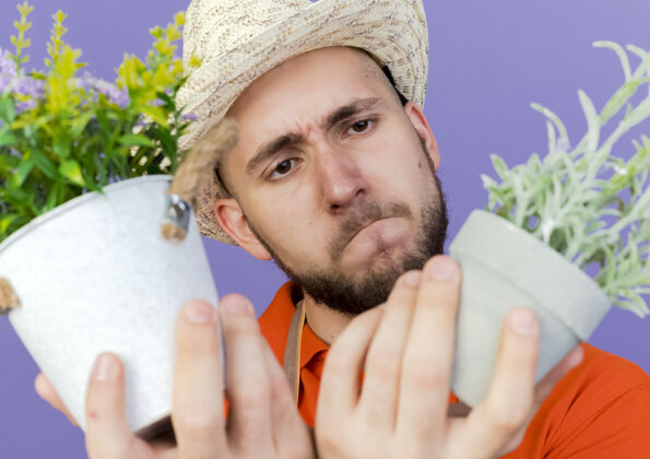 男困惑的男园丁戴着园艺帽看着花盆里的花花园艺困惑