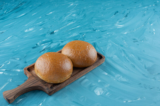 面包房新鲜的棕色面包放在一块木板上 背景很浅膳食白面包美味