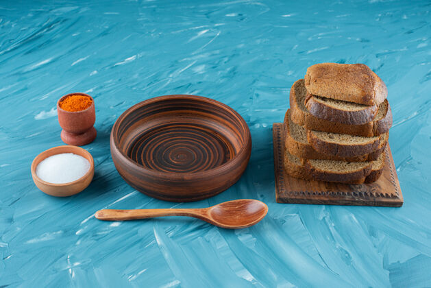 棕色用盐和蓝色背景的空木勺切的棕色面包空的面包木头