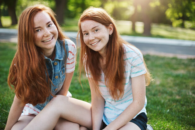 生姜满头红发 满脸雀斑的欧洲姐妹们坐在绿草上 笑容满面 和朋友们一起野餐 表达着喜悦和娱乐情感和家庭观念欢乐情感关系