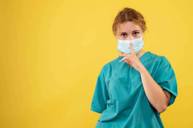女人黄墙上年轻女医生穿着医疗服 戴着口罩的正面图医院护士年轻女医生