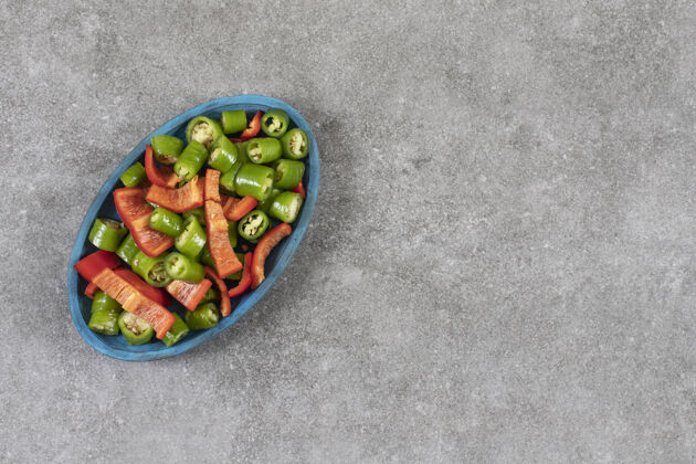 成熟把辣椒和甜椒片放在盘子里 放在大理石桌上营养盘子有机