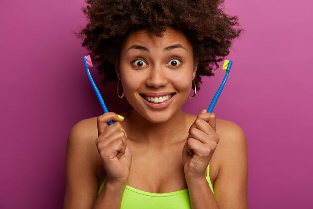 牙齿很高兴惊讶的黑人妇女拿着两个牙刷新鲜室内牙刷
