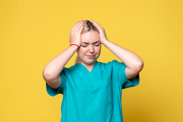 痛苦黄墙上年轻女医生穿着医用衬衫头痛的正面图人衬衫成人