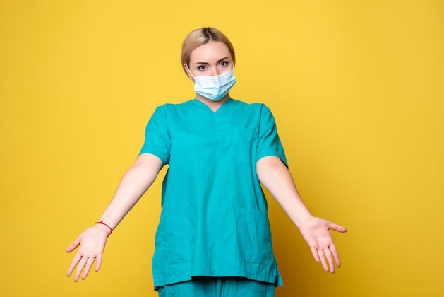 消毒黄色墙壁上穿着医用衬衫和无菌口罩的年轻女医生的正面图模特年轻女医生面具