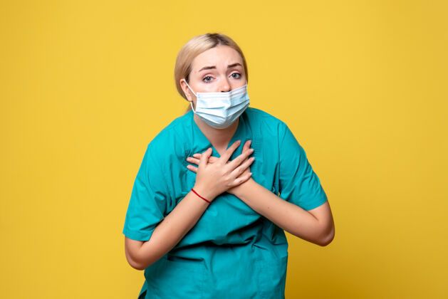 情绪黄墙上年轻女医生穿着医用衬衫 戴着口罩的正面图正面微笑快乐
