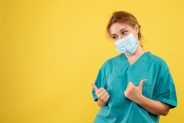 健康黄墙上年轻女医生穿着医疗服 戴着无菌口罩的正面图医院正面套装