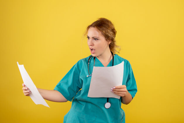 持有黄墙上穿着医疗服的女医生手持分析图护士病毒人