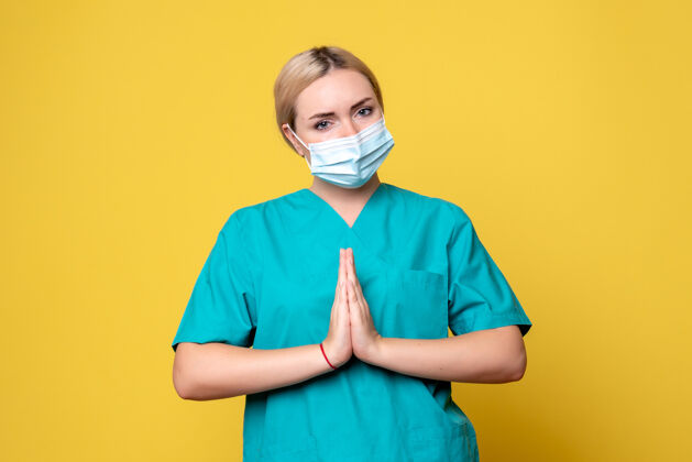人黄色墙壁上穿着医用衬衫和无菌口罩的年轻女医生的正面图年轻女医生医生医疗
