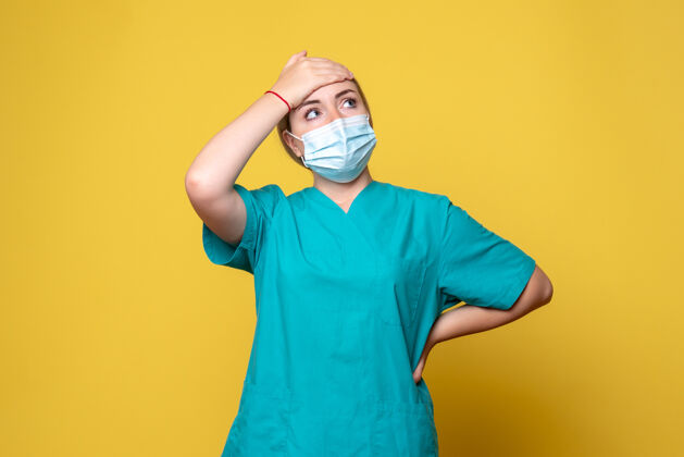 人黄色墙壁上穿着医用衬衫和无菌口罩的年轻女医生的正面图人正面成人