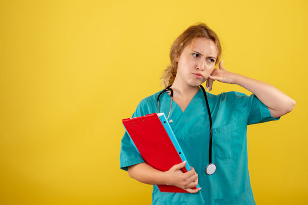 健康黄墙上穿着医疗服拿着不同分析的女医生正面图听诊器分析医生