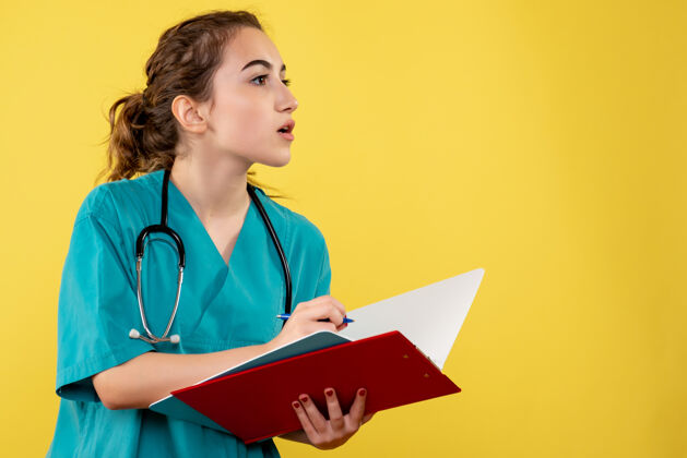 大流行穿着医用衬衫的女医生在黄色墙上写笔记的正面图医生健康病毒