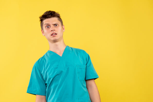 成人黄色墙壁上 穿着医疗服的男医生脸上带着困惑医学男医生自信