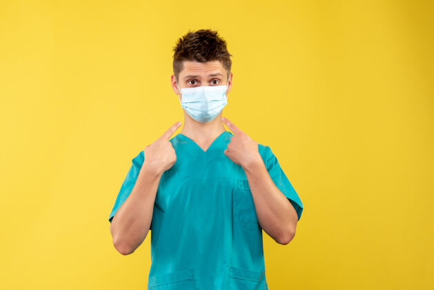 医院黄墙上穿着医疗服 戴着防护面罩的男医生的正面图人保护疾病