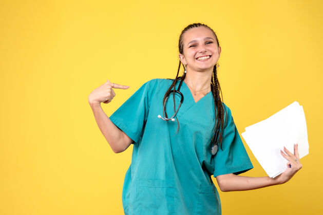 情绪黄墙上穿着医疗服拿着纸的女医生的正视图护士肖像病毒