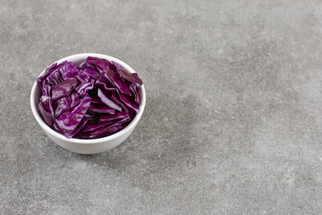 蔬菜石桌上放着一碗白的紫色卷心菜新鲜切片卷心菜