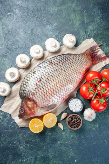 膳食顶视图新鲜的生鱼肉与红色西红柿和蘑菇在深蓝色的背景健康食物番茄