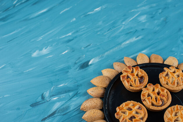 黄色一圈杏仁和新鲜甜甜的圆形饼干 背景是蓝色的新鲜食物美味