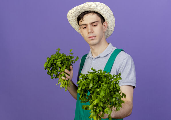 帽子自信的年轻男园丁戴着园艺帽 拿着香菜看信心复制胡荽
