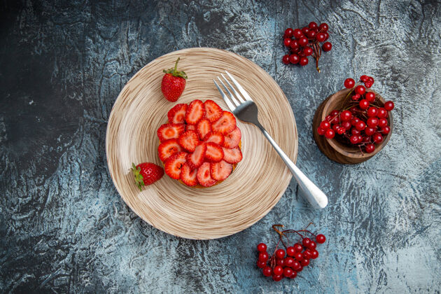 浆果在黑暗的桌子上俯瞰美味的草莓蛋糕和浆果新鲜灌木水果