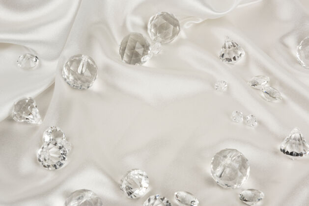 平放白色织物纹理背景上的装饰性透明钻石清晰鸟瞰豪华