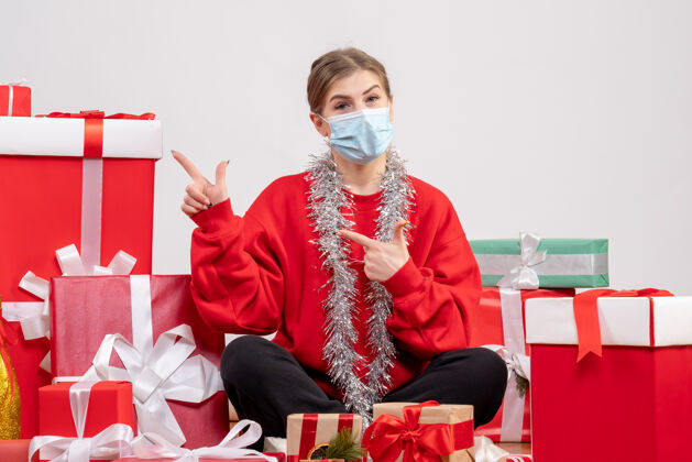 病毒正面图：年轻女性戴着无菌面具坐着 手里拿着圣诞礼物礼物绝育圣诞节