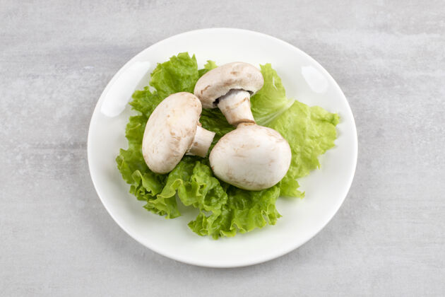 蘑菇蘑菇放在莴苣叶上 放在盘子里 放在大理石桌上健康叶整个