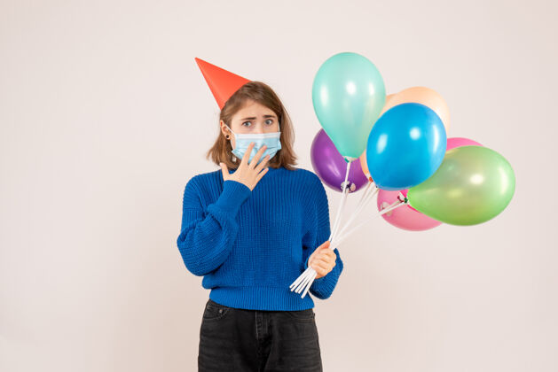 气球正面图：戴着消毒面具的年轻女性手持五颜六色的气球病毒五颜六色聚会