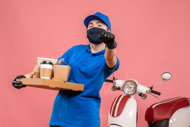 面具正面图：女快递员 在粉色大流行的工作服上送咖啡和食物 送货员covid-制服服务工作送货工作