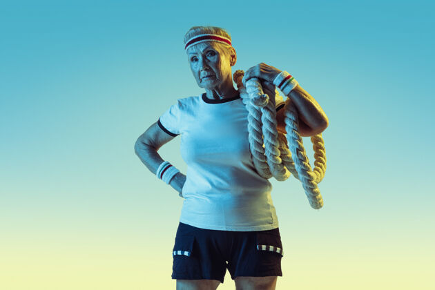 人高级女子运动装训练与绳索梯度背景 霓虹灯运动微笑比赛