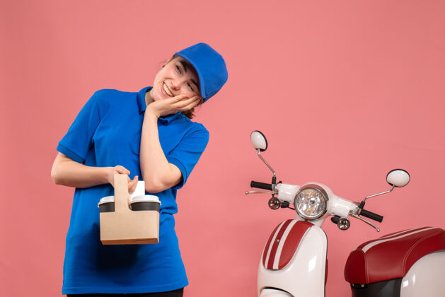 女人正面图：女快递员在粉色办公桌上送咖啡送货服务工女自行车制服工球员工作人