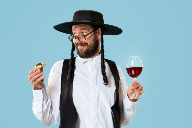 文化这位年轻的东正教犹太男子戴着黑帽子 在犹太普瑞姆节上吃哈曼塔森饼干律法犹太教耳朵