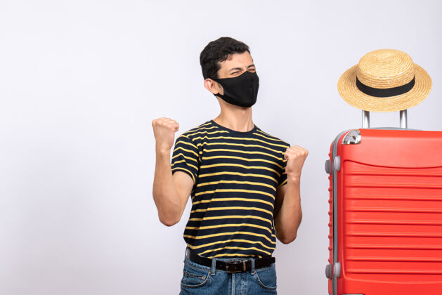 手提箱正面图戴着黑色面具的快乐年轻游客站在红色手提箱旁男前面成人