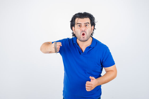 愤怒成熟男子的肖像威胁与链子包裹着拳头在蓝色t恤和前瞻性的正面视图消极老愤怒