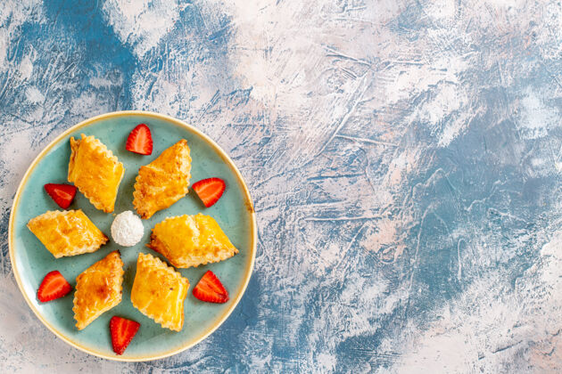 盘子俯瞰美味的甜蛋糕与草莓蓝色背景美食蛋糕正餐