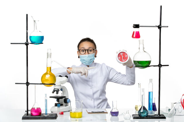 医疗前视图：穿着医疗服的女化学家 戴着面罩 背景是浅白色的病毒实验室化学冠状病毒飞溅西装视图科学