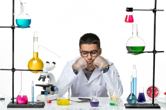 医学正面图身着医疗服的男性化学家坐在白色背景上感到疲惫病毒冠状病毒飞溅疾病科学实验室感觉科学