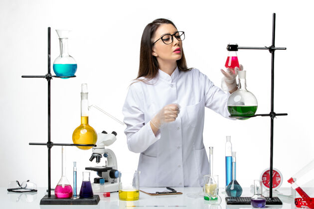 罐子前视图：穿着无菌医疗服的女化学家在白色背景病毒上用不同的溶液工作-大流行科学医学溶液烧杯