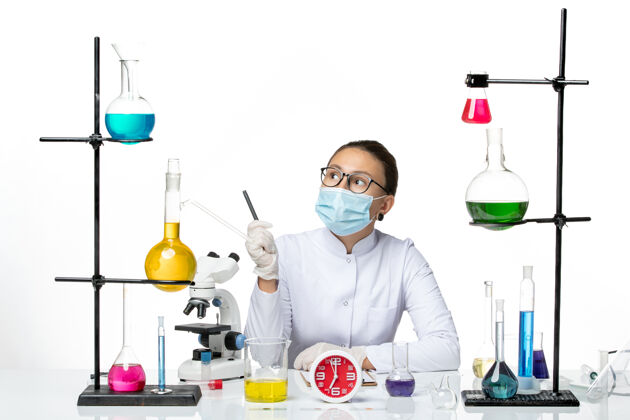病毒前视图：身穿白色医疗服的女化学家 戴着面罩 手持笔 背景为浅白色 化学家病毒covid-splashlab套装药品化学家