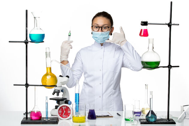 正面前视图身穿医疗服的女化学家 戴着面罩 在浅白色背景上注射病毒化学实验室的covidsplash医生专业医疗