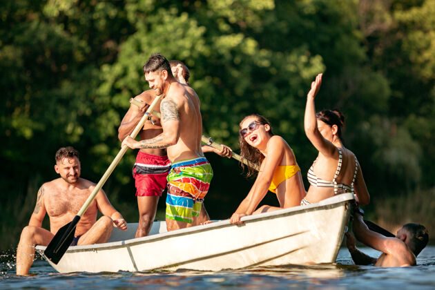 漂亮一群快乐的朋友在河里欢笑和游泳阳光明媚的日子里 穿着泳装的男女们在河边乘船欢庆夏日 友谊 度假 周末的概念新鲜友谊泳装