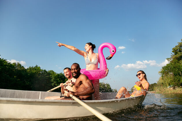 湖泊一群快乐的朋友在河里欢笑和游泳阳光明媚的日子里 穿着泳装的男女们在河边乘船欢庆夏日 友谊 度假 周末的概念欢呼背部时刻