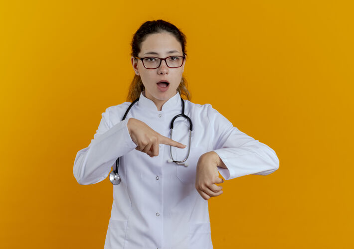长袍年轻女医生穿着医用长袍 戴着眼镜听诊器 显示腕表的手势听诊器医疗时钟