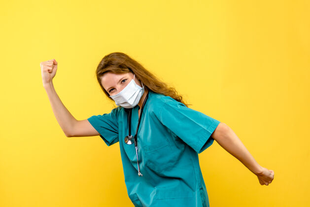 女医生黄色墙壁上戴着面具的女医生的正视图医疗保健医院情感