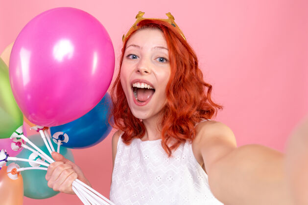 飞机正面近景年轻女子手持五颜六色的气球在粉红色上欢呼雀跃人人成人
