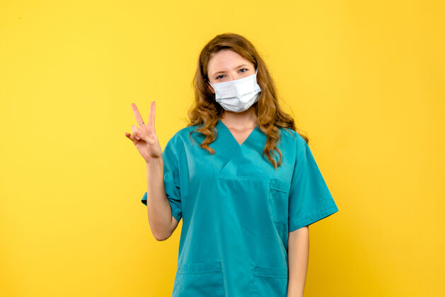 医疗保健黄色墙壁上戴着面具微笑的女医生的正视图职业微笑面具