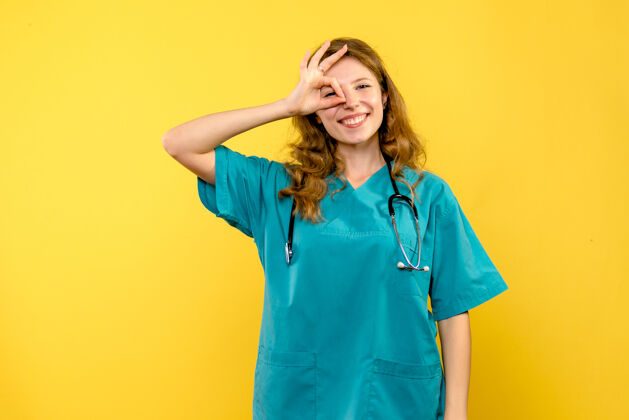 制服黄色墙上微笑的女医生的正面图正面医院黄色