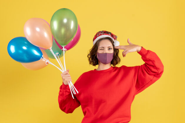 派对正面图：黄色地板上戴着消毒面具手持气球的年轻女性新年彩女情感派对庆祝活动颜色面具生日